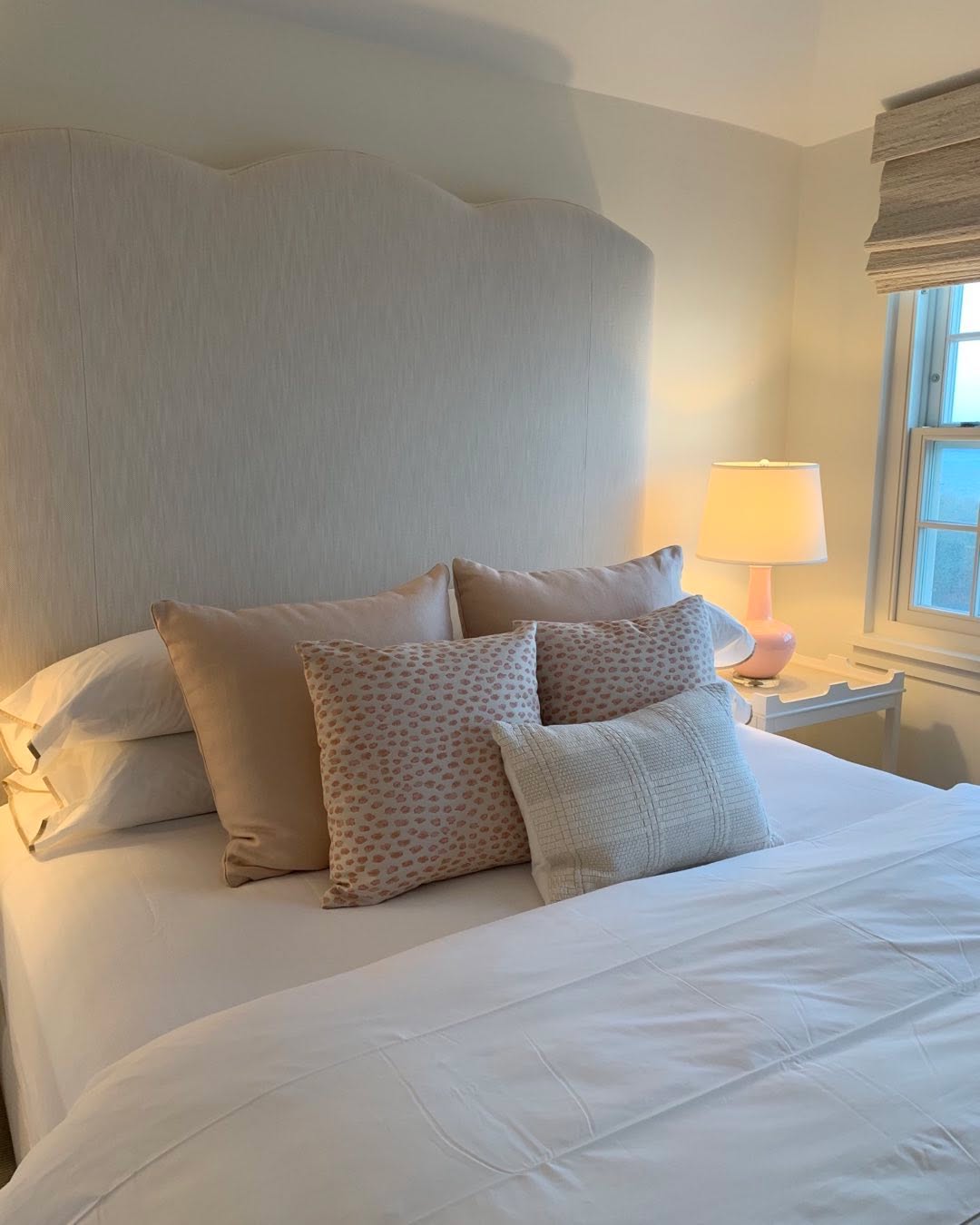 Bedroom with a scalloped upholstered headboard and layered white bedding