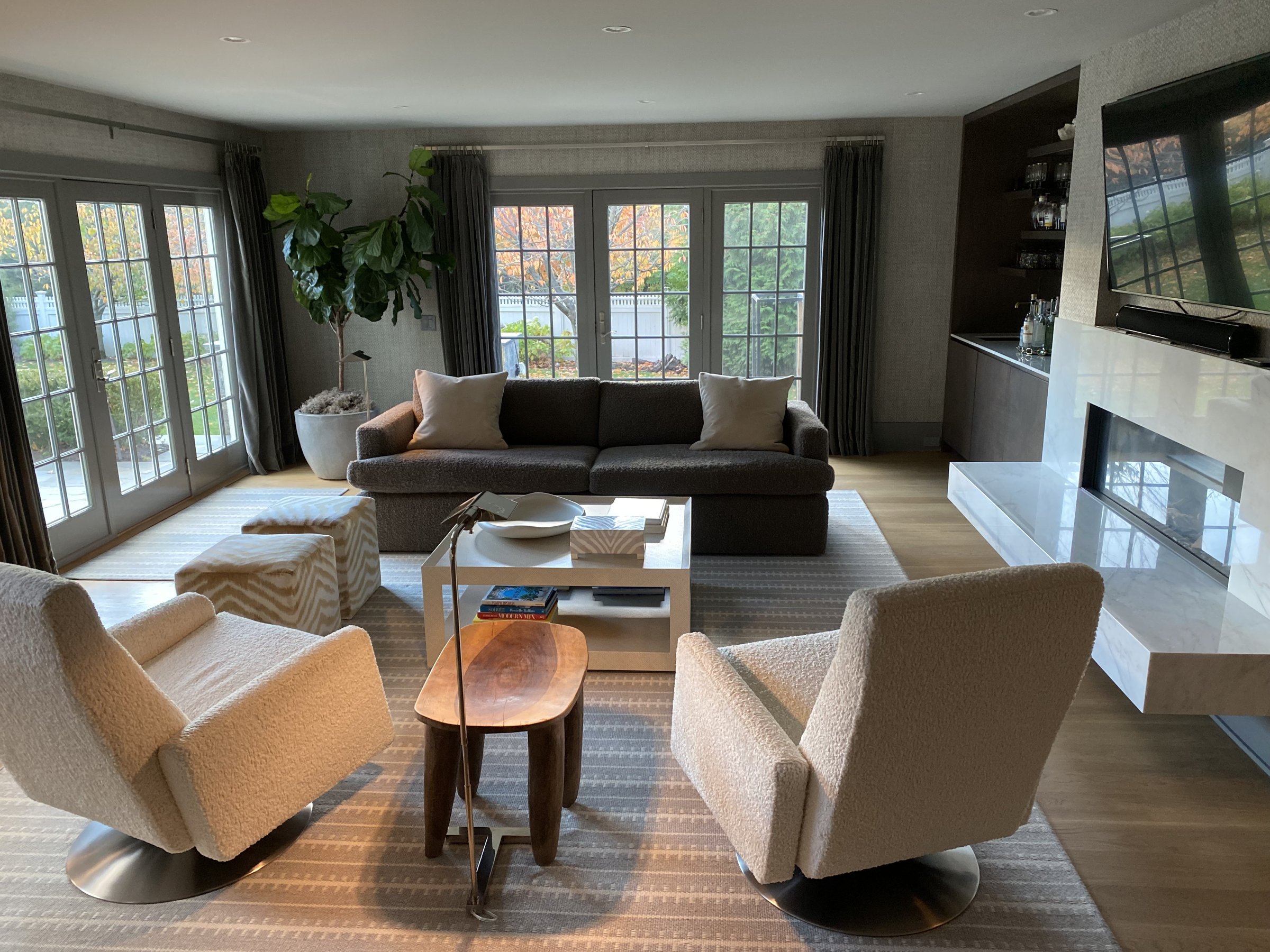 Family room with a charcoal sofa, boucle swivel chairs and a stone fireplace