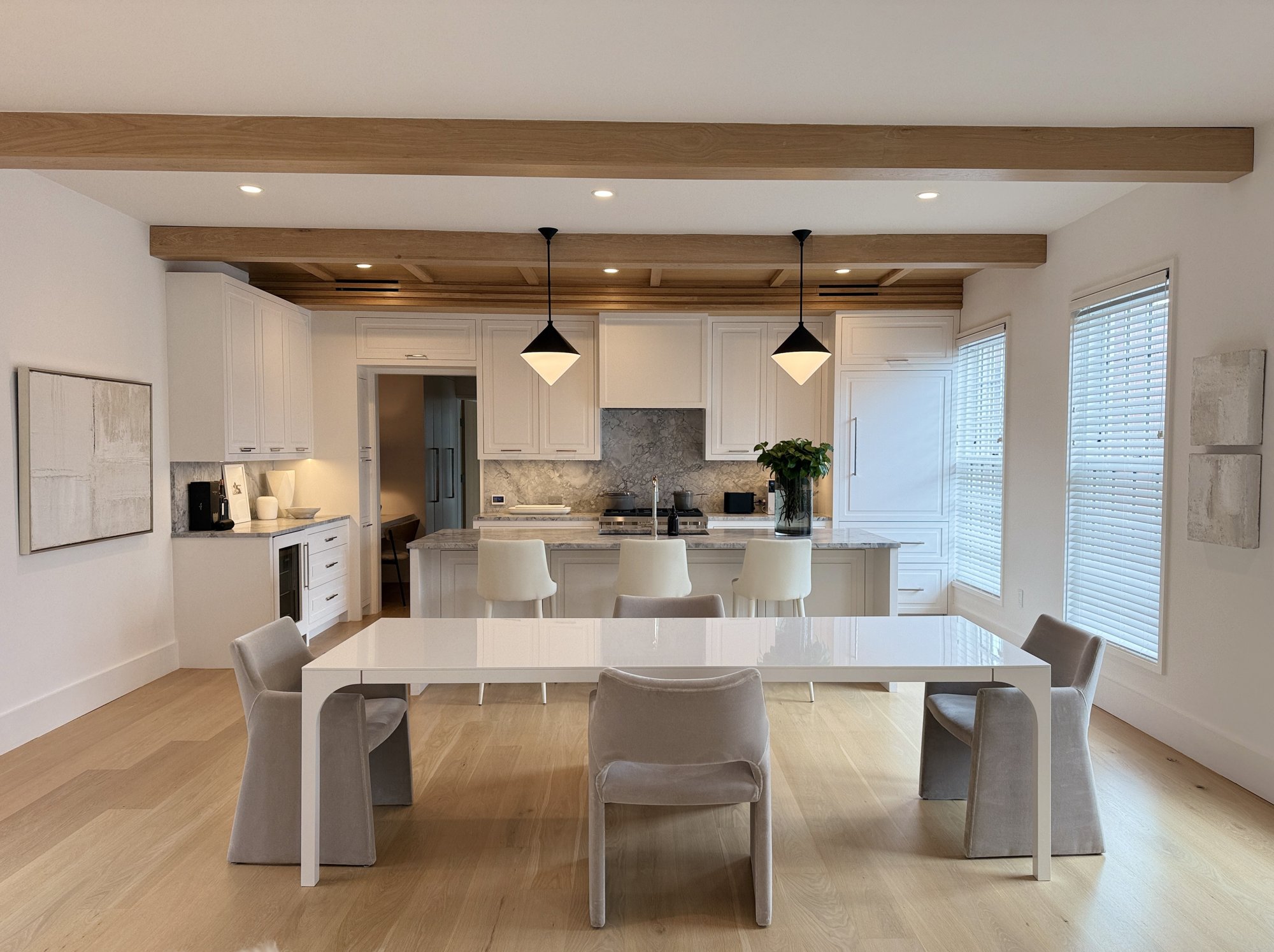 Open kitchen and dining room in white and pale oak beneath exposed beams