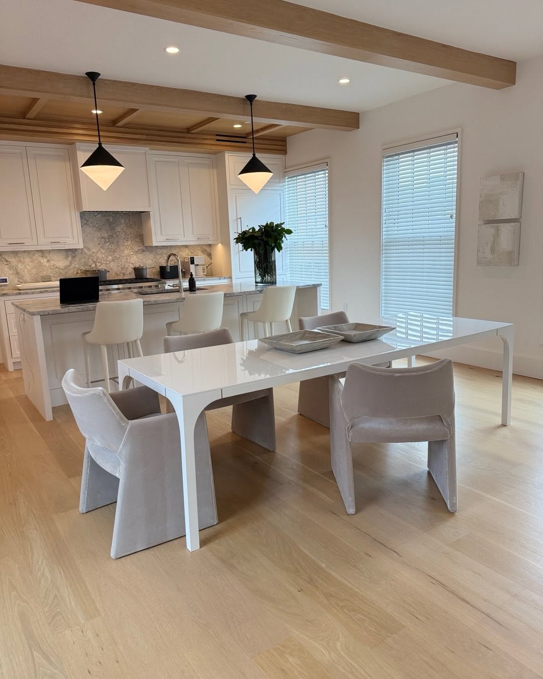 Open kitchen and dining room in ivory and pale oak beneath exposed beams