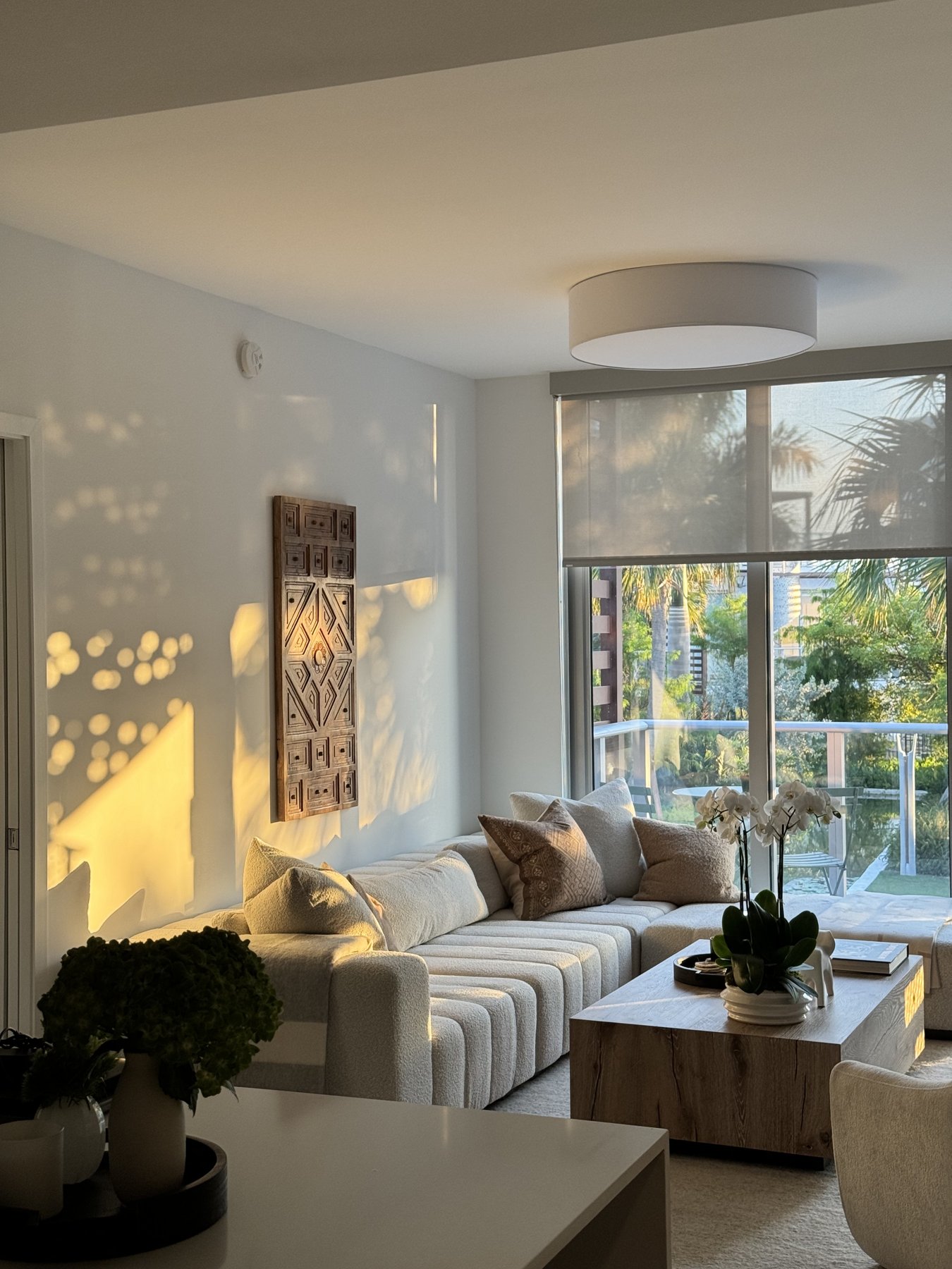 Living room sectional in low evening light, palms beyond the balcony