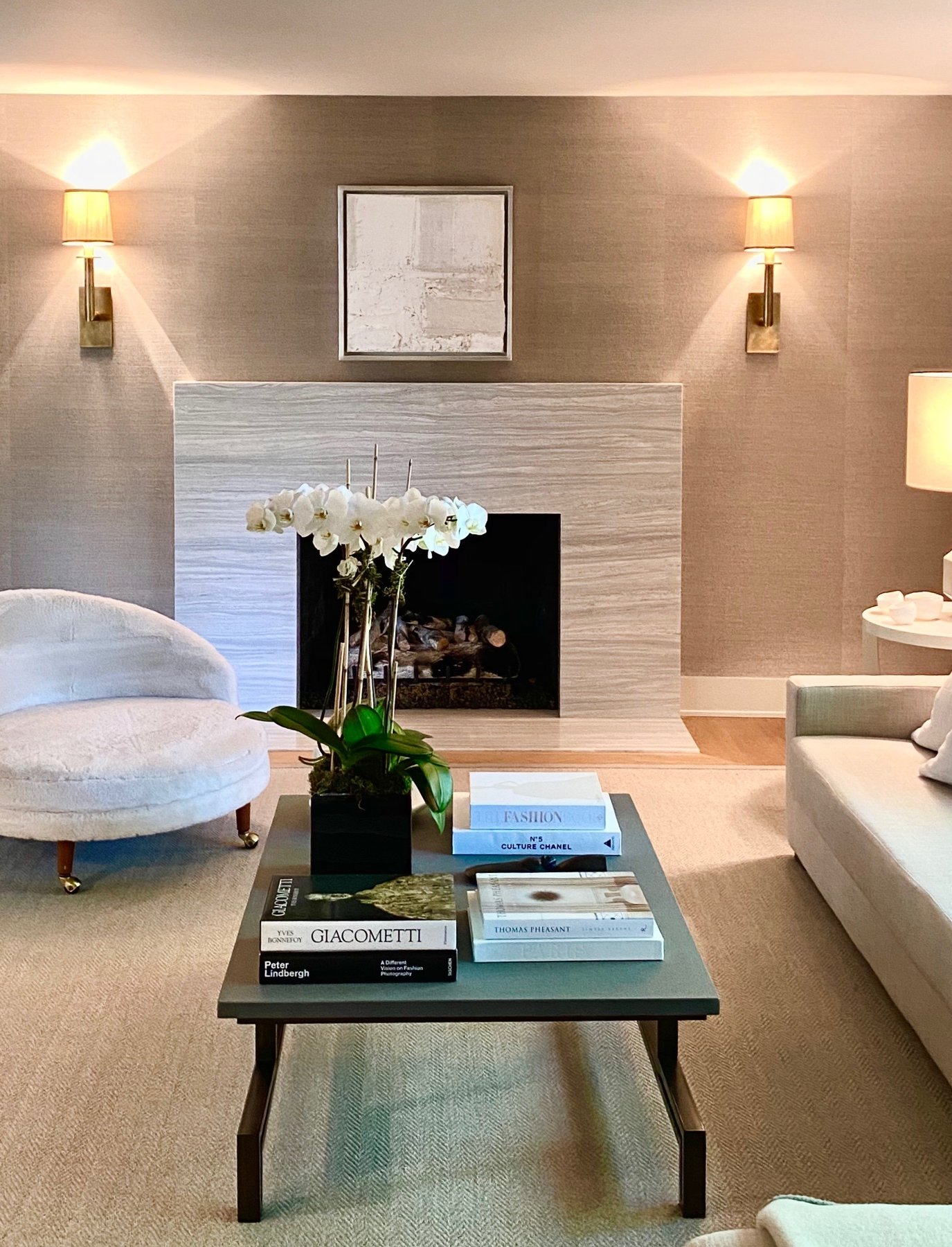 Living room with a limestone fireplace, grasscloth walls and white orchids