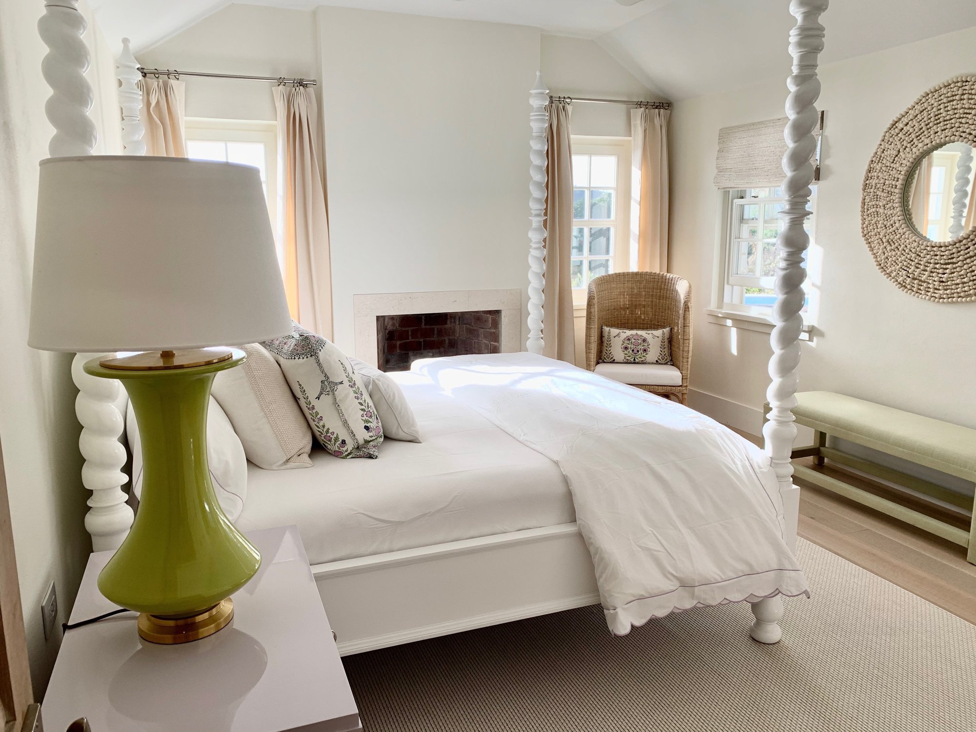 White four-poster spindle bed with a fireplace and a green lamp