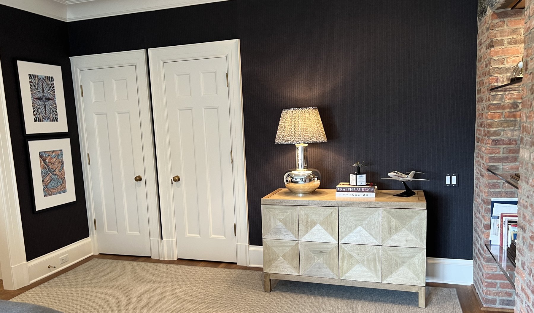 Study with a faceted credenza, a silver lamp and exposed brick